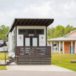 Modern tiny home with dark wood siding and front steps at Sugar Sands RV Resort.