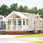 Tiny home rental with white siding and covered front porch at Sugar Sands RV Resort.